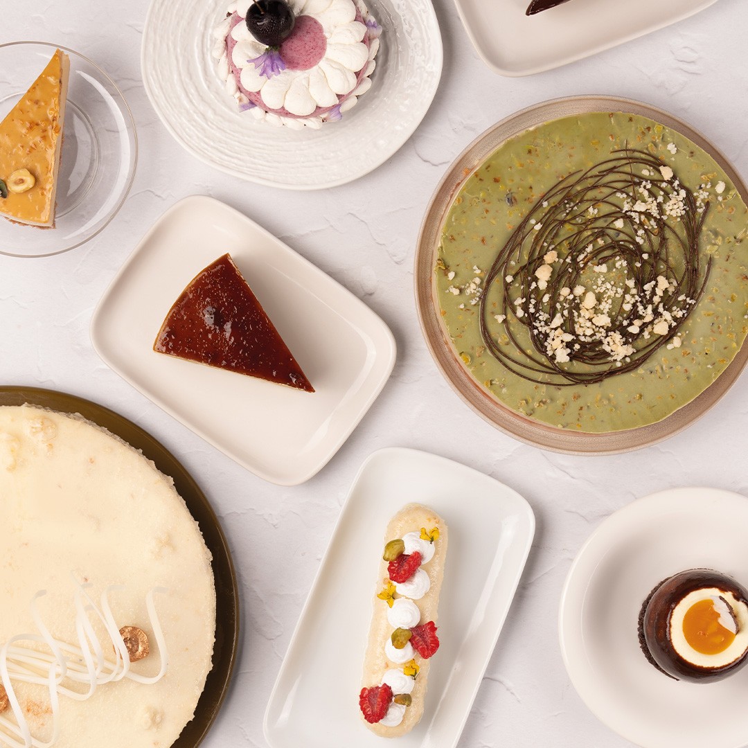 Góc nhìn từ trên xuống các loại bánh tráng miệng gồm bánh phô mai, flan, tart hồ trăn, eclair và mousse socola trong ly